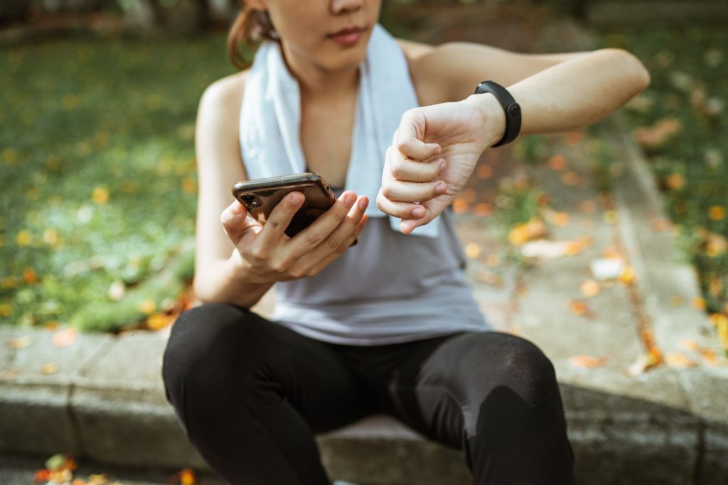 Woman Holding Phone and Using Health Tracker
